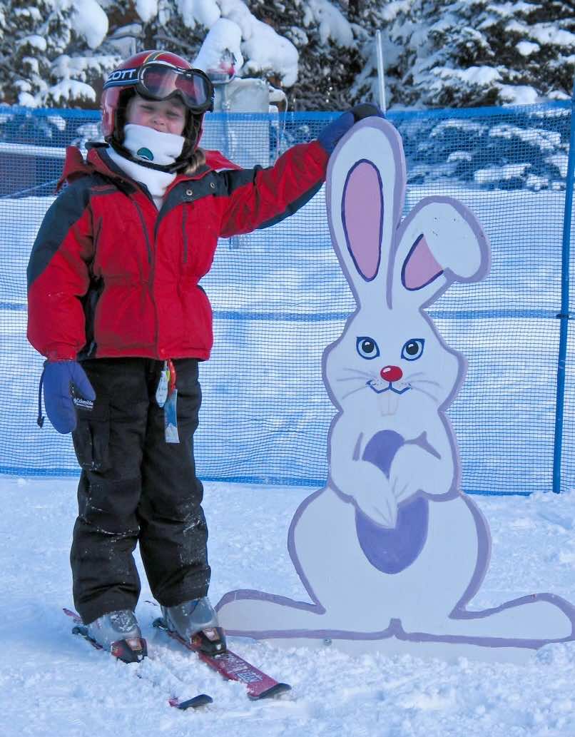 Child stands by Rabbit sign at Ski School