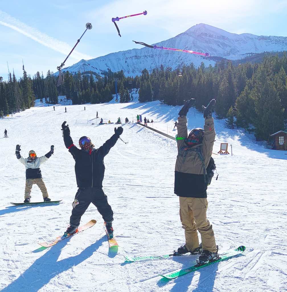 People in ski gear throwing their poles in the air