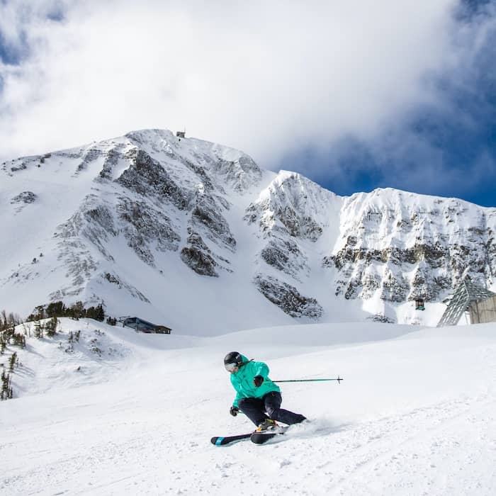 Skier on a groomed run in front of Lone Peak