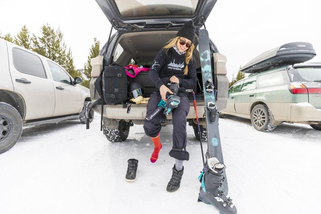 Woman putting ski boots on in her car